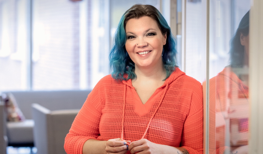 Leende kvinna lutar sig mot en vägg