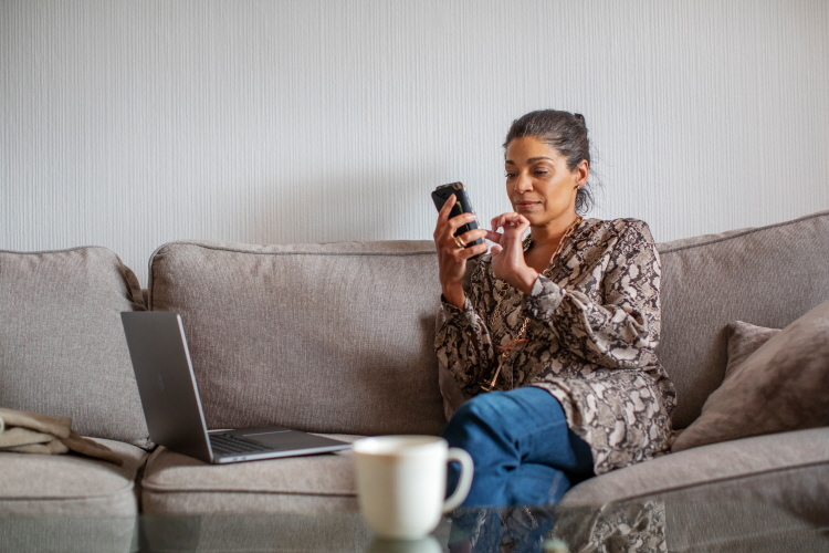 Person som sitter i soffa med en telefon i handen.